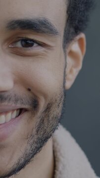 Close-up portrait of cheerful African American man half face smiling looking at camera on black studio background. People and emotion concept.