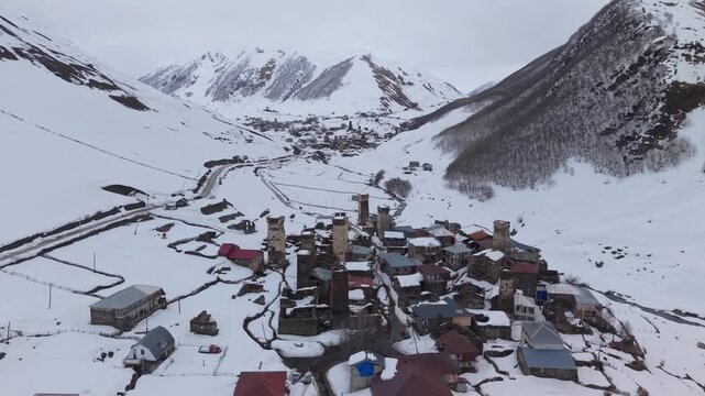 Aerial footage showcasing Ushguli covered in snow, with iconic Svan towers, traditional stone houses, and the dramatic snow-covered Caucasus Mountains surrounding the historic village.