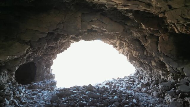 Camera moves through a dark volcanic cave at Fortaleza de Ansite as the exposure opens to reveal the Barranco de Tirajana mountains in Gran Canaria