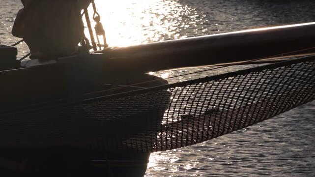 Cinematic Silhouette of Catamaran Bow and Trampoline Net Against Golden Sunset Water Reflections