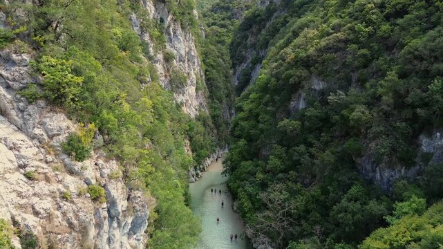 Drone pulls back to reveal Acheron River between forested cliffs in Greece