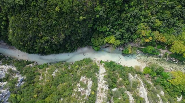Drone slowly descends over Acheron River between forested slopes in Greece