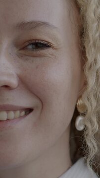 Close-up portrait of cheerful young woman half face smiling looking at camera on black studio background. People and positive emotion concept.