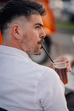 Man drinking refreshing beverage with straw outdoors