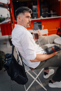 Digital nomad man drinking coffee holding tablet outdoor