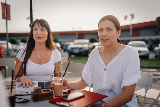 Women colleagues having business meeting outdoors with coffee