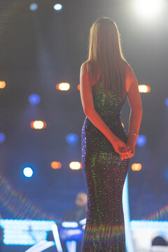Elegant woman in sparkling green dress on stage with copy space