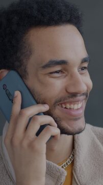 Slow motion of joyful African American man speaking on mobile phone on black studio background. Cellphone communication and people concept.