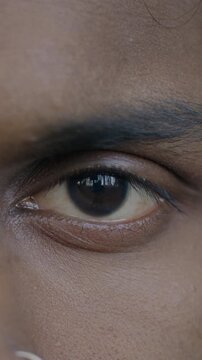 Close-up slow motion portrait of male eyes looking at camera while Indian man expressing no emotion. People and face expression concept.