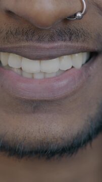Close-up portrait of male mouth smiling while anonymous man with nose piercing feeling happy expressing joy. People and emotion concept.