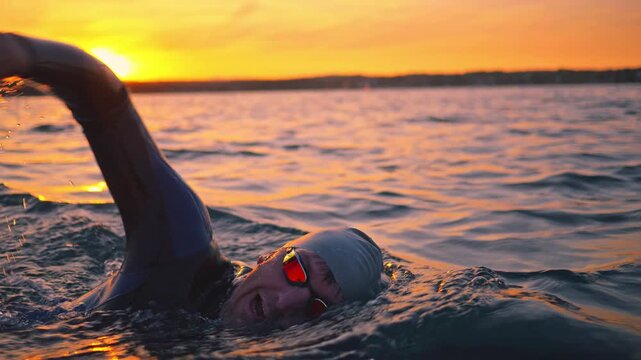 A swimmer in a wetsuit battles waves against a stunning sunset, embodying determination and commitment in their sport training. Each stroke reflects the challenge of mastering the water.