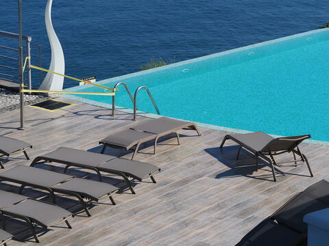 View of the infinity pool with sun loungers against the backdrop of the sea, and the hotel grounds.