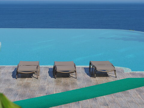 View of the infinity pool with sun loungers against the backdrop of the sea, and the hotel grounds.