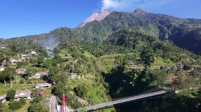 Aerial drone view of Girpasang suspension bridge with majestic Mount Merapi volcano background in Tegalmulyo, Klaten, Indonesia