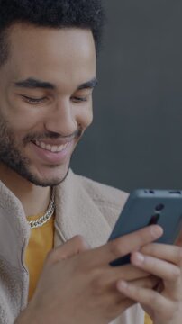 African American man using smartphone texting then sending audio message on black background. Modern technology and people concept.