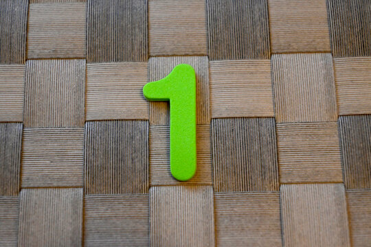 Green number one on woven wooden background