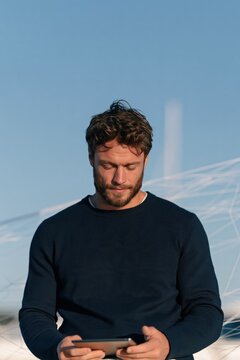 Bearded man using tablet outdoors with soft sky and subtle network lines for corporate background and remote work banner