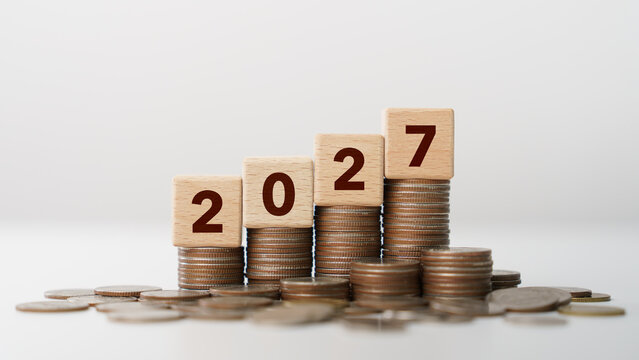 Stacks of coins with wooden blocks forming number 2027 for target financial growth, investment planning, money savings to wealth, business goals concept. Budget and tax, Happy new year 2027
