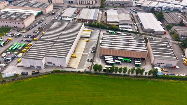 Aerial hyperlapse of yellow delivery vans leaving a logistics facility following loading operations