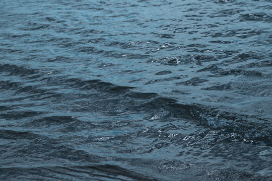 Gentle blue  water with small waves and ripples reflecting soft light on a calm sea.