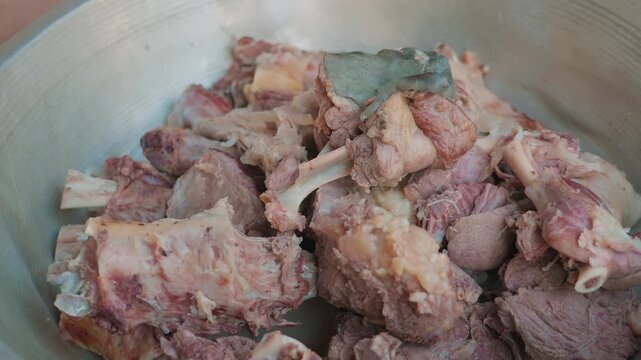 Close-up of large pieces of boiled meat for pilaf in aluminum bowl