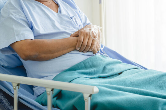 Mature Male Patient with IV Line Injection on Hand Resting on Hospital Bed