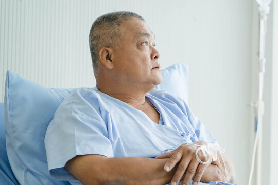 Mature Male Patient with IV Line Injection on Hand Resting on Hospital Bed