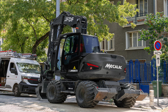 Nancy, France - July 22nd 2026 : View of a 15-tonne black compact wheeled excavator Mecalac 15MWR on a construction site for work on the drinking water network.