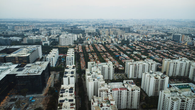 Aerial view of rapidly expanding real estate development in Bangalore, Karnataka, India, featuring large residential apartment complexes, ongoing construction, and a dense urban landscape.