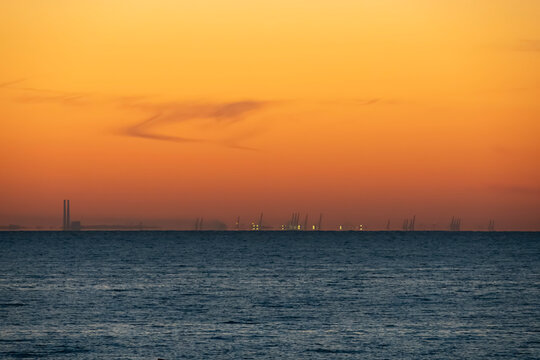 Luc-Sur-Mer, France - 08 08 2026: Fishermen's Pier. Colorful sunrise over the sea from the beach and the port of Le Havre far away