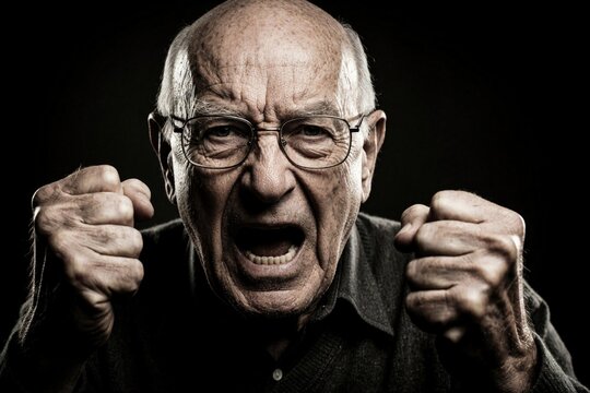 Angry senior caucasian man shouts with intense emotion. Mature male businessman clenches fists in rage. Grumpy elderly person screams loudly expressing frustration anger. Close up portrait of mad old