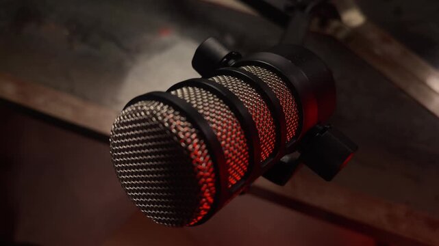 Professional condenser microphone in a recording studio with dramatic red lighting. Smoke or vapor drifts in the background of the setup