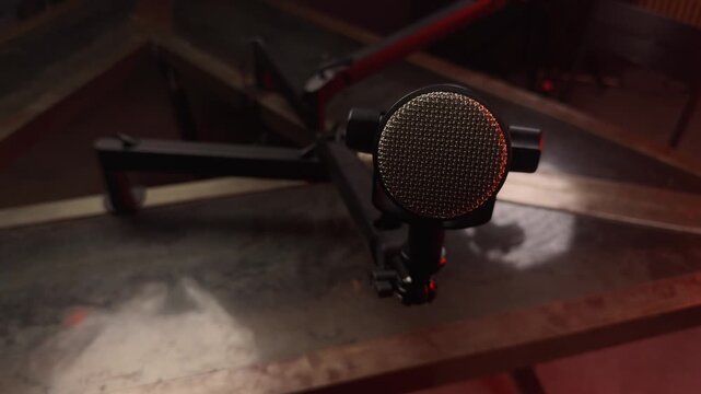 Professional condenser microphone on a stand in a dark, moody studio with red ambient light. Stage smoke floats around the audio equipment