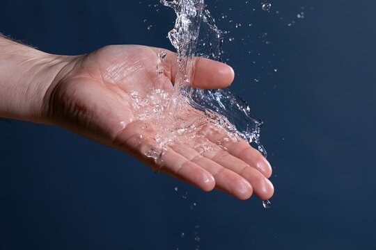 The Hand Catching Water Splash in Clear Blue Background Scene