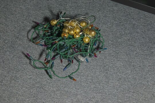 String lights tangled on gray carpet in preparation for festive event
