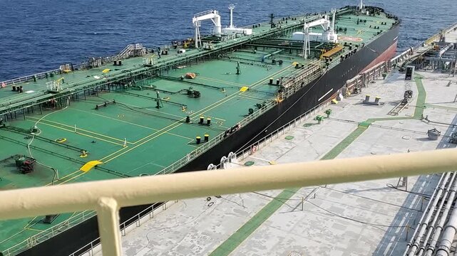 Horizontal view of ship to ship transfer operation with two oil tankers moored alongside with tensioned lines rolling in open ocean swell. High quality FullHD footage