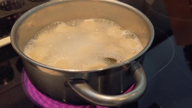 Cooking food in a boiling pot on the stove while bubbles rise and steam escapes