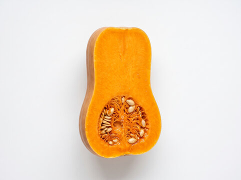 Cross section cut of an orange ripe butternut pumpkin showing inner cavity and seeds isolated on white.