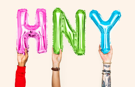 Hands holding balloons spelling HNY