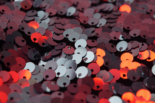 Close-up of red and silver sequins on fabric, glittering texture with bokeh effect
