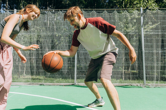 A father and daughter play basketball together on an outdoor court
