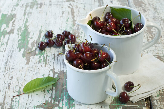 Two enamel pots of cherries