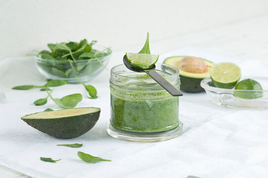 Glass of spinach avocado lime smoothie and ingredients