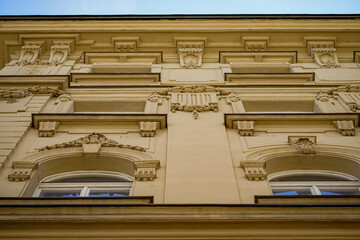Close-up architectural view of an ornate historic facade featuring classical decorative reliefs, arched windows and symmetrical detailing in warm beige tones. © Duro Mesiar