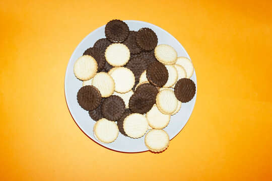 Plate of black and white sandwich cookies on an orange background