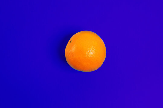 A fresh orange sits on a blue background