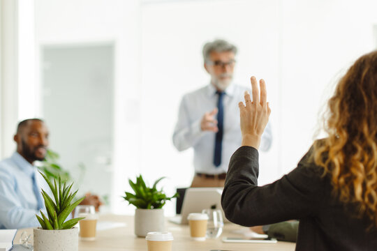 Businesswoman raises hand to ask question during office meeting
