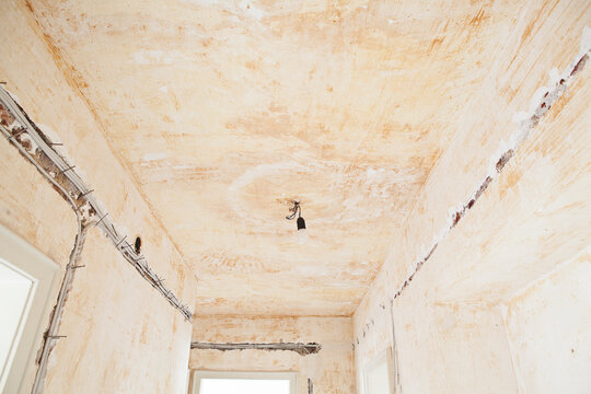 An empty room undergoes renovation with exposed wiring on the wall