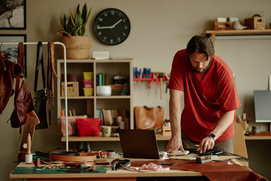 Male artisan creates handmade leather goods in his workshop