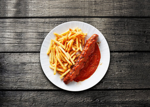 A traditional German currywurst and fast food sit on a wooden table